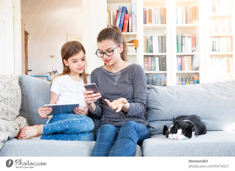 Two sisters sitting on the couch at home using electronic devices Germany tablet digitizer Tablet Computer Tablet PC Tablet Computers iPad Digital Tablet
