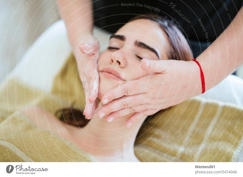 Young woman receiving facial beauty treatment in a spa (value=0) towels cosmetic cream creams skin cream lounges massage touch relax relaxing relaxation enjoy