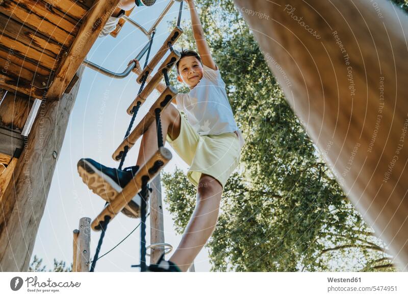 Boy climbing ladder in public park on sunny day color image colour image outdoors location shots outdoor shot outdoor shots daylight shot daylight shots