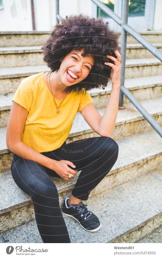 Portrait of laughing young woman sitting on stairs outdoors human human being human beings humans person persons curl curled curls curly hair T- Shirt t-shirts