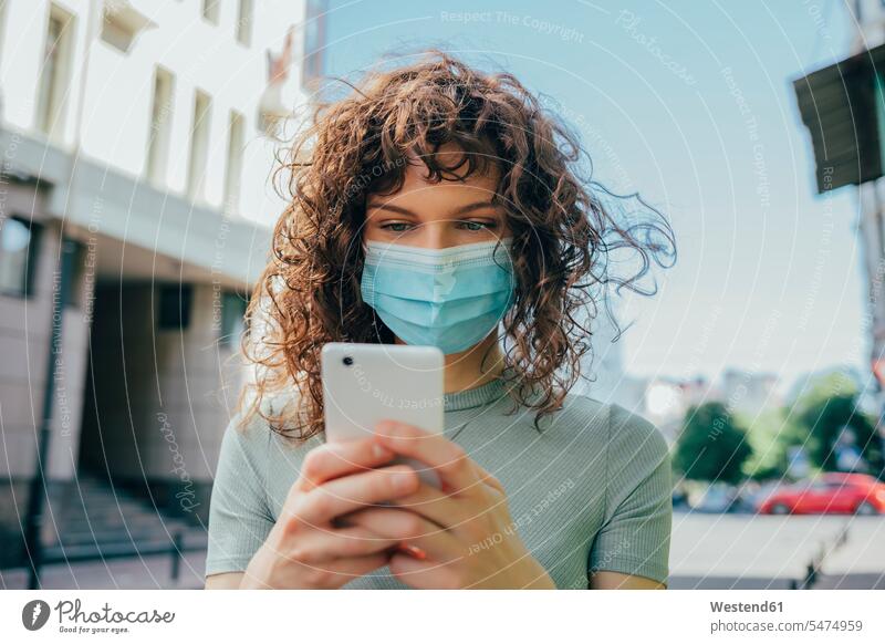 Woman wearing protective mask and using smartphone in city telecommunication phones telephone telephones cell phone cell phones Cellphone mobile mobile phones