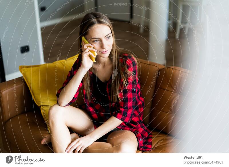 Young woman on cell phone on a couch at home human human being human beings humans person persons celibate celibates singles solitary people solitary person