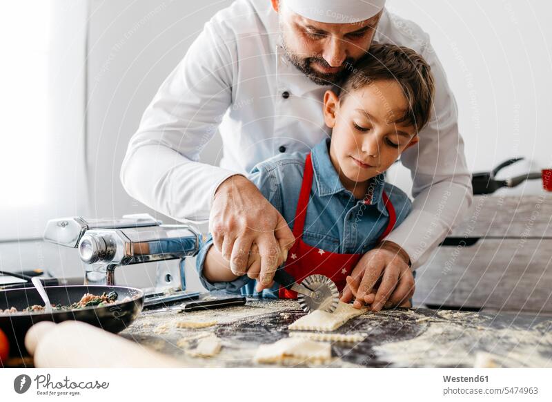 Father and son cutting homemade gluten free pasta with pasta cutter Chefs cook cooks learn at home funny having fun supporting Co-Operation collaborate