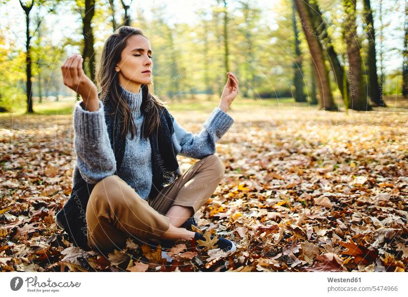 Young woman meditating in autumn forest Seated sit enjoyment free Liberty free time leisure time concentrate concentrated concentrating meditate meditations
