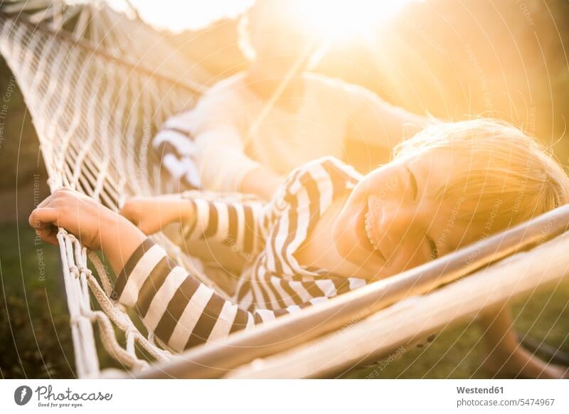 Portrait of smiling boy lying in hammock with father in background hammocks in the evening Late Evening seasons summer time summertime summery relax relaxing