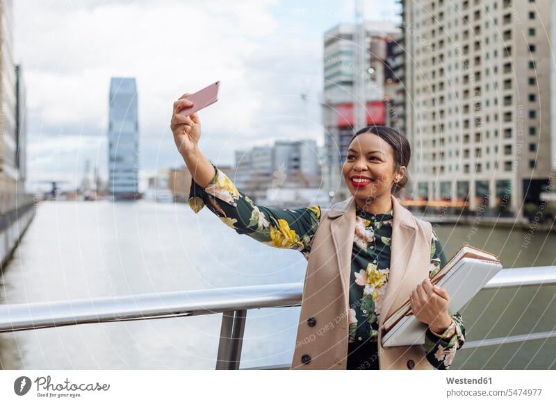 UK, London, portrait of fashionable businesswoman taking selfie with cell phone portraits Smartphone iPhone Smartphones businesswomen business woman