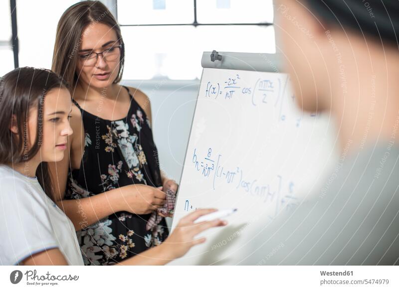 Teacher helping teenage girl writing formula on whiteboard teacher instructor teachers white board school schools assistance assisting Help Classroom