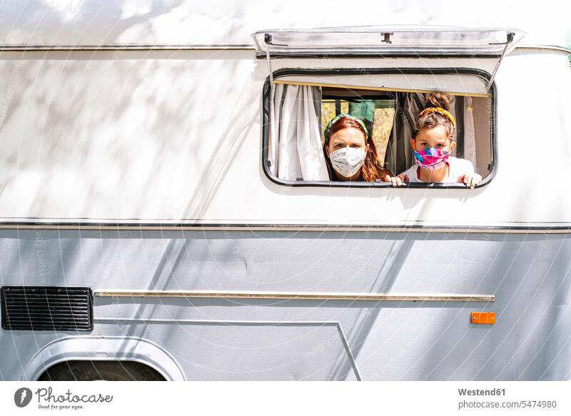 Mother and daughter wearing masks looking through window of motor home color image colour image Spain leisure activity leisure activities free time leisure time