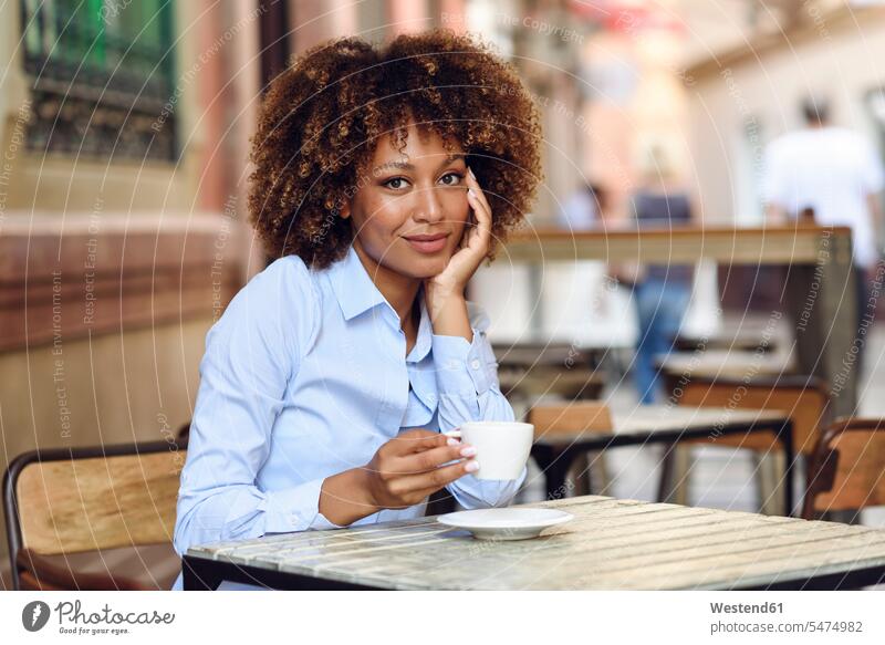 Portrait of smiling woman with afro hairstyle sitting in outdoor cafe smile Afro Afros portrait portraits Seated females women people persons human being humans