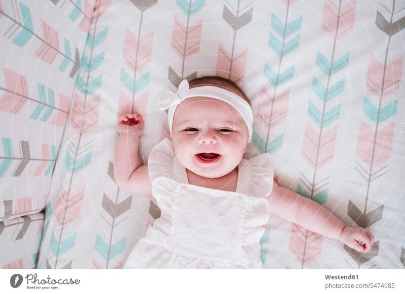 Cheerful baby girl lying in crib at home color image colour image indoors indoor shot indoor shots interior interior view Interiors day daylight shot