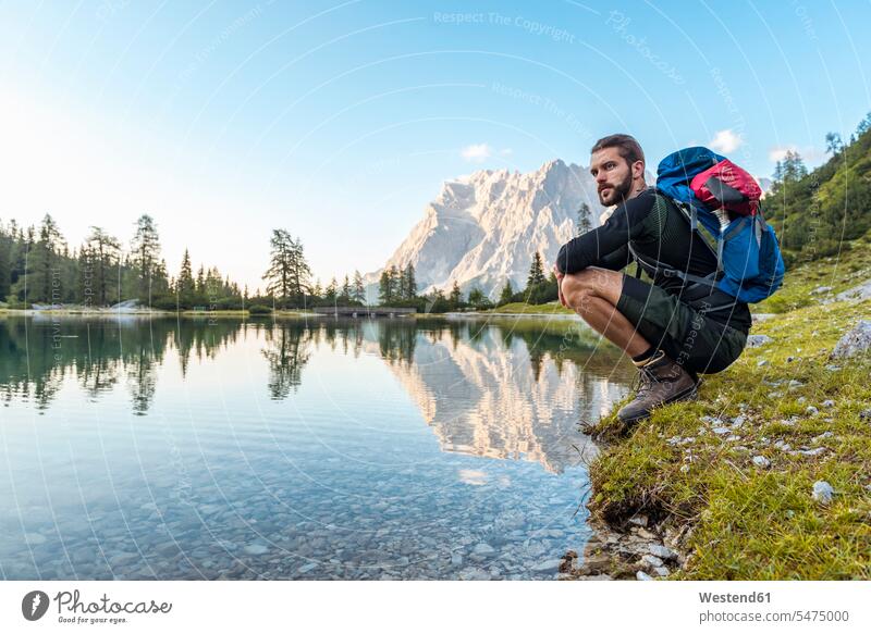 Austria, Tyrol, Hiker taking a break, crouching by the lake Taking a Break resting Lakeshore Lake Shore lakeside hiker wanderers hikers cowering