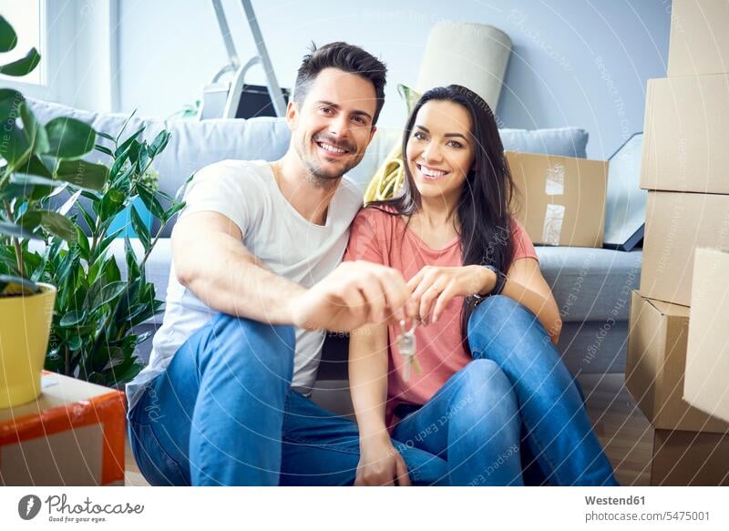 Portrait of happy couple moving in showing keys to new apartment happiness move in holding twosomes partnership couples portrait portraits cardboard box