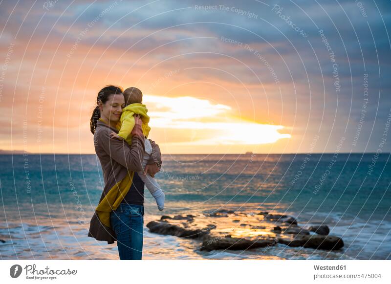Mother holding little daughter on the beach at sunset mother mommy mothers ma mummy mama daughters baby infants nurselings babies sunsets sundown beaches