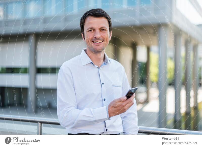 Portrait of smiling businessman with cell phone in the city portrait portraits mobile phone mobiles mobile phones Cellphone cell phones Businessman Business man