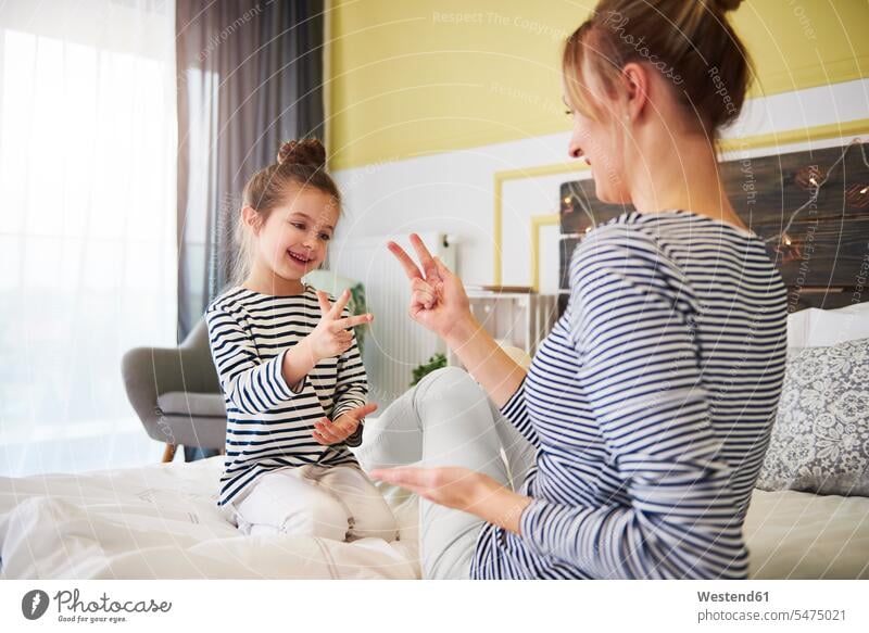 Mother and daughter having fun together, playing, sitting on bed beds mother mommy mothers ma mummy mama girl females girls daughters Fun funny home at home