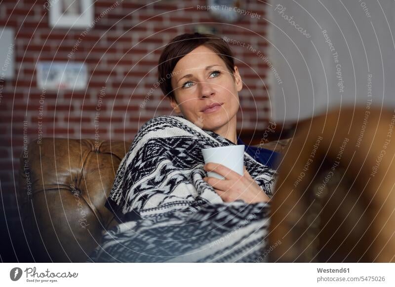Woman on sofa relaxing at home, drinking tea relaxed relaxation woman females women Tea Teas lying laying down lie lying down daydreaming day dreaming Daydreams