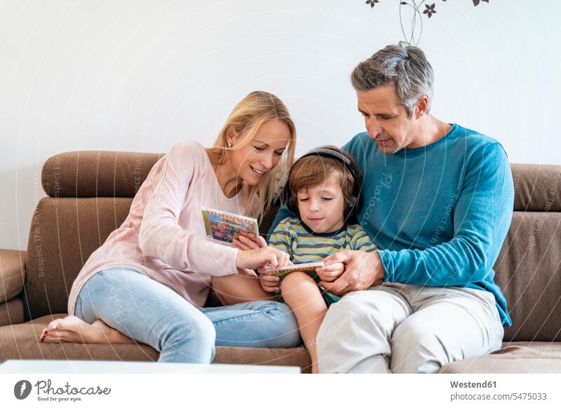 Family on couch at home with boy listening to music with headphones couches settee settees sofa sofas headset CD ROM CD-ROM CDs Compact Disc Compactdisc hear