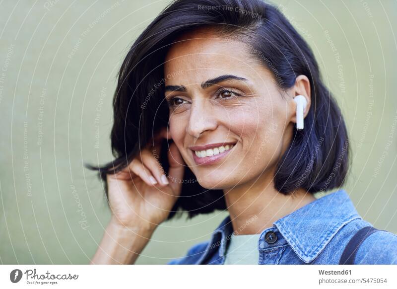 Close-up of smiling businesswoman wearing wireless headphones against wall color image colour image Germany businesswomen business woman business women