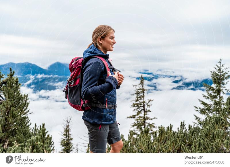 Smiling young woman on a hiking trip in the mountains, Herzogstand, Bavaria, Germany touristic tourists back-pack back-packs backpacks rucksack rucksacks go