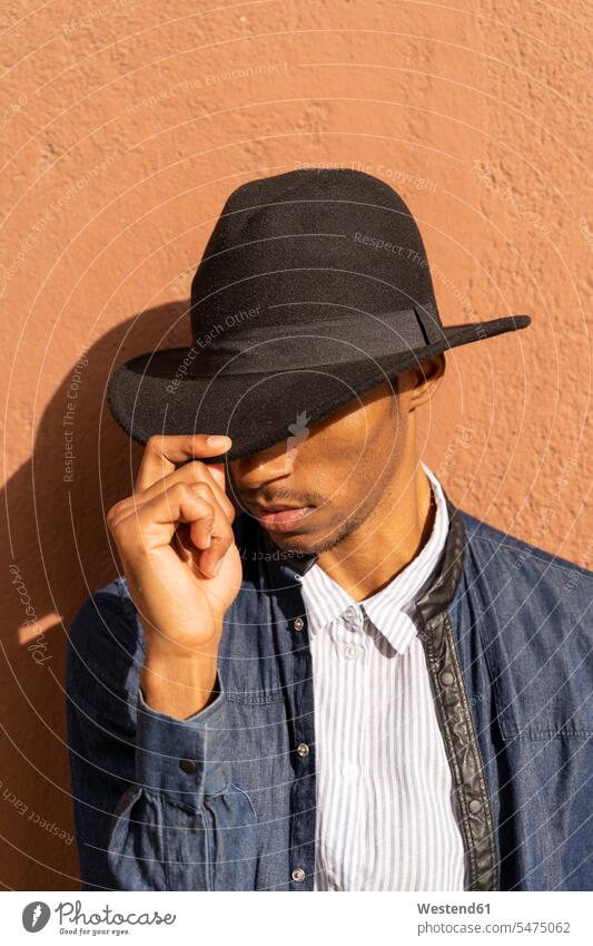 Stylish young man wearing a hat at a wall human human being human beings humans person persons African black black ethnicity coloured African American