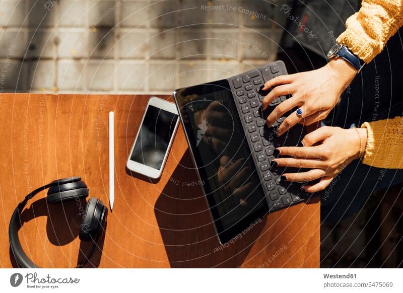 Hands of female student typing on digital tablet keyboard while sitting at sidewalk cafe in city color image colour image Spain outdoors location shots