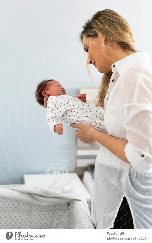 Mother holding her newborn baby multicultural infants nurselings babies innocence innocent Guiltless shirt shirt blouse happiness happy eyes closed closed eyes