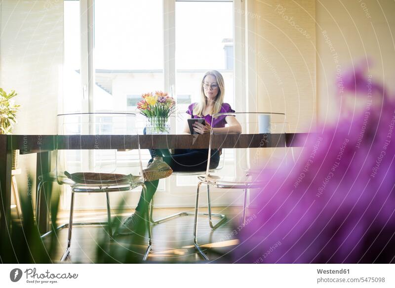 Businesswoman sitting at meeting table using tablet businesswoman businesswomen business woman business women use meeting tables Seated business people