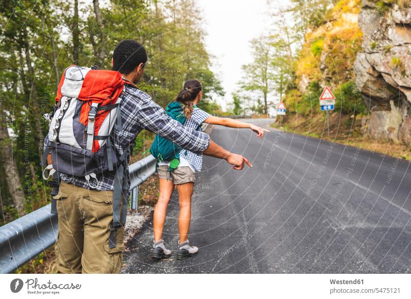 Italy, Massa, couple hitchhiking on a road in the Alpi Apuane mountains hitchhike hitch-hiking roads twosomes partnership couples people persons human being