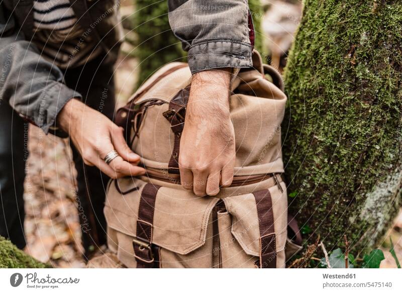 Man closing his backpack, close up back-pack back-packs backpacks rucksack rucksacks seasons hibernal free time leisure time forests wood woods location shot