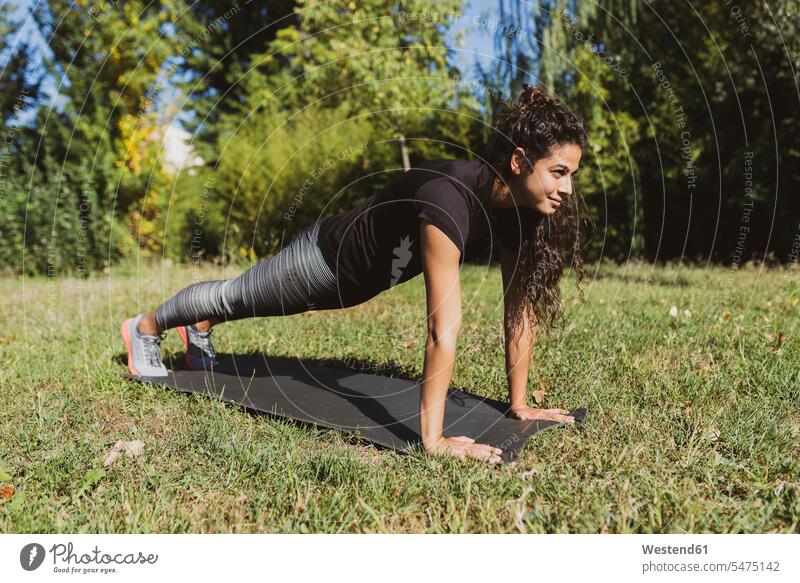 Sporty young woman doing push-ups on a meadow meadows exercising exercise training practising sportive sporting sporty athletic females women sports Adults