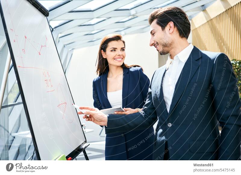 Businessman and businesswoman working with flip chart in office Business man Businessmen Business men At Work flipchart flip charts flipcharts businesswomen