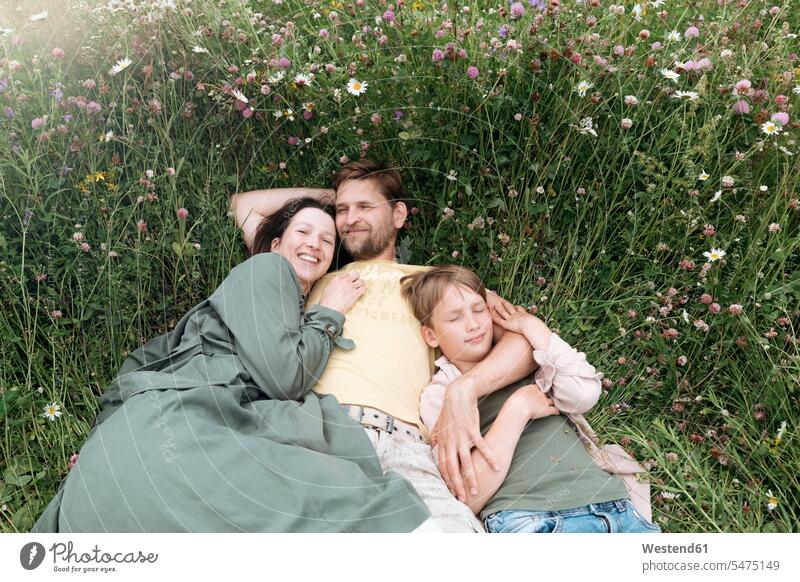 Smiling parents with son lying on land amidst flowers color image colour image leisure activity leisure activities free time leisure time casual clothing