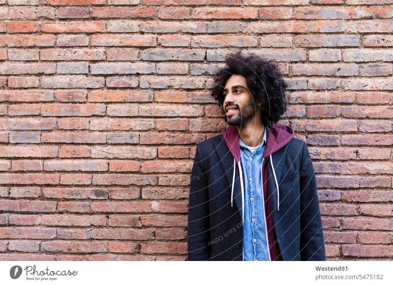 Portrait of a smiling young man standing at a brick wall brick walls portrait portraits men males smile Adults grown-ups grownups adult people persons