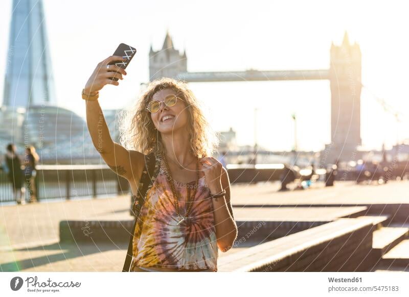 UK, London, smiling young woman taking a selfie with Tower Bridge in background Selfie Selfies smile females women bridge bridges happiness happy Adults