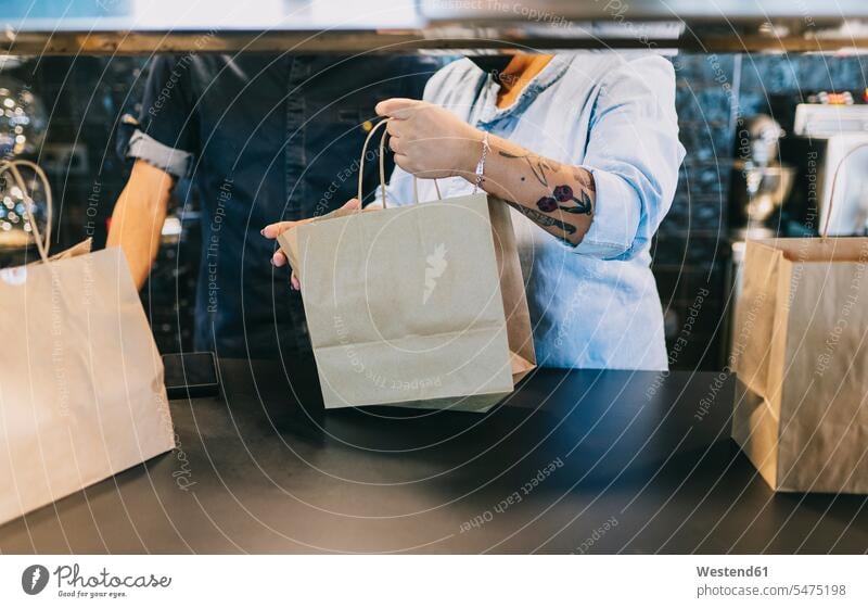 Midsection of chefs working together while holding paper bags at restaurant kitchen counter color image colour image indoors indoor shot indoor shots interior