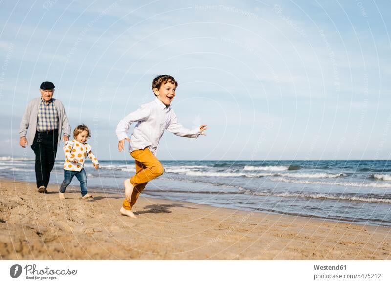 Grandfather strolling with his grandchildren on the beach Energy Vigour Vigor Spiritedness Vitality Power Enjoyment Amusement pleasure enjoy enjoying Fun