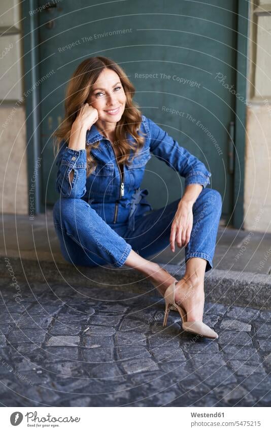 Mature woman wearing denim jumpsuit, sitting on the ground pants Trouser Denim Jeans shoes high heel high heeled shoe high heeled shoes Stiletto Stiletto Heels