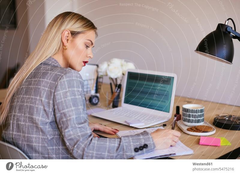 Young businesswoman working in office, using laptop sitting Seated businesswomen business woman business women blond blond hair blonde hair At Work offices