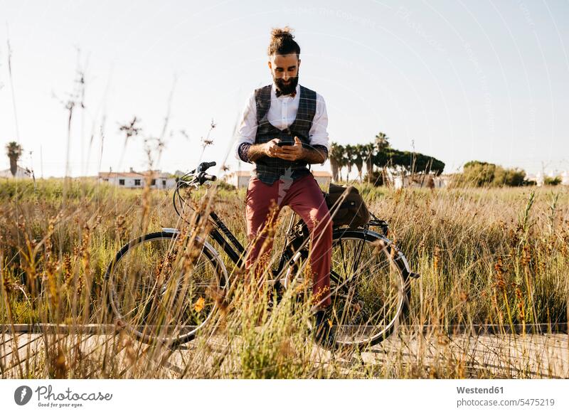 Well dressed man with his bike on a wooden walkway in the countryside using cell phone human human being human beings humans person persons caucasian appearance