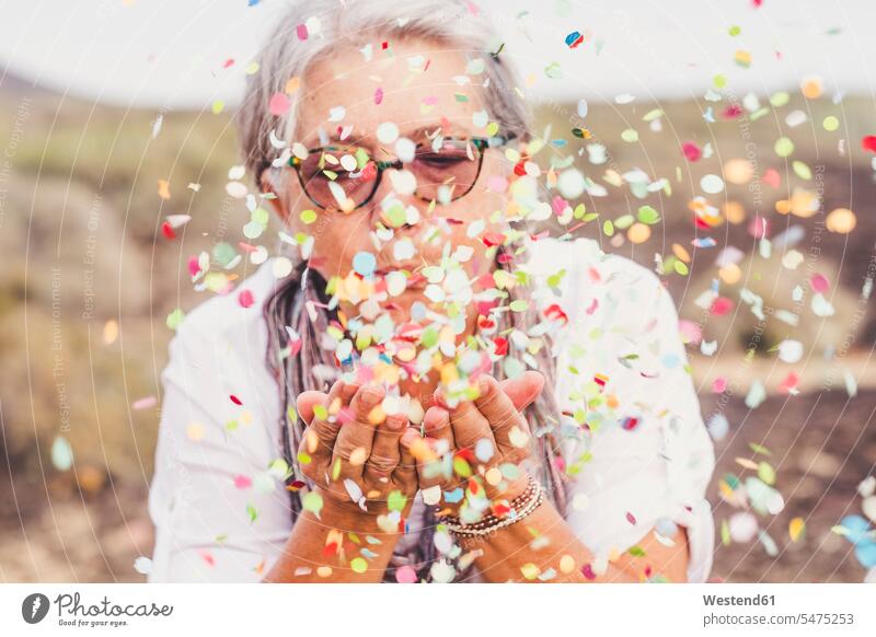 Senior woman blowing confetti outdoors caucasian caucasian ethnicity caucasian appearance european carefree Party Parties day daylight shot daylight shots