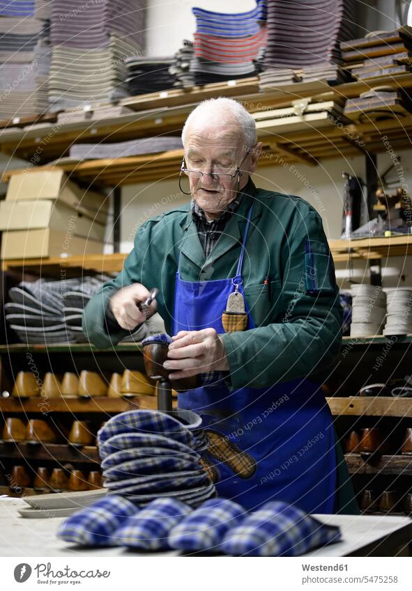 Senior shoemaker working on slippers in workshop cobbler At Work senior men senior man elder man elder men senior citizen craftsman trade craftsmen