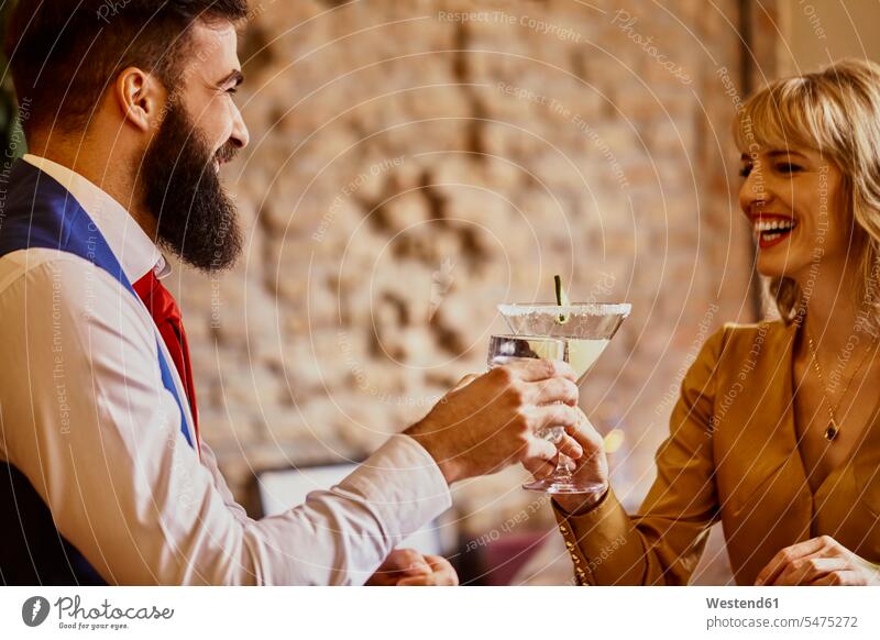 Happy elegant couple toasting glasses in a bar Glass Drinking Glasses chic elegance stylishly classy twosomes partnership couples bars happiness happy clinking