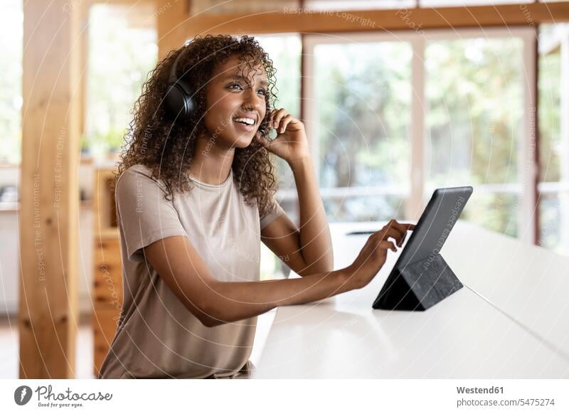 Businesswoman with digital tablet talking through headphones while sitting at home color image colour image indoors indoor shot indoor shots interior
