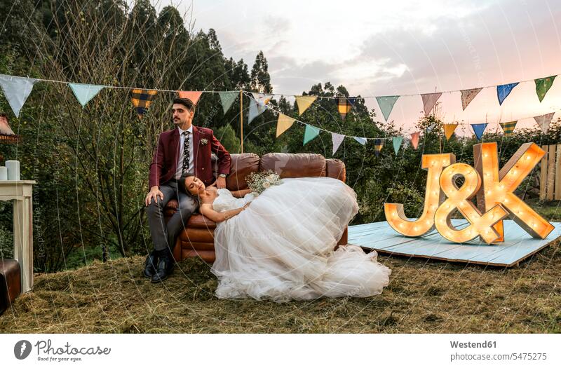 Bride lying over sofa with groom in the field Field Fields farmland bridal couple bridal couples bride brides couch settee sofas couches settees bridegrooms