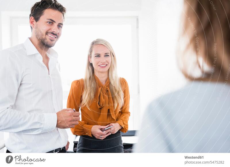 Happy male and female business colleagues discussing in office color image colour image indoors indoor shot indoor shots interior interior view Interiors day