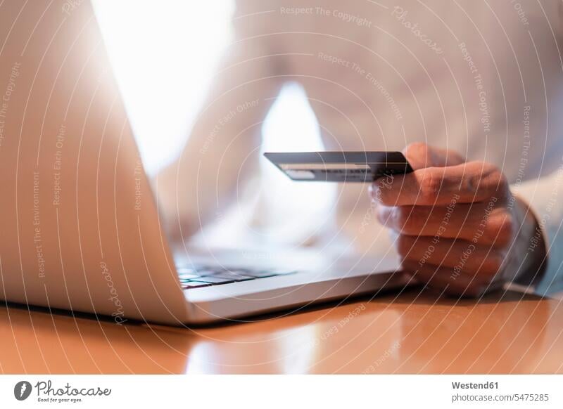 Man's hands holding credit card and while making an online payment with laptop, close-up Businessman Business man Businessmen Business men online shopping