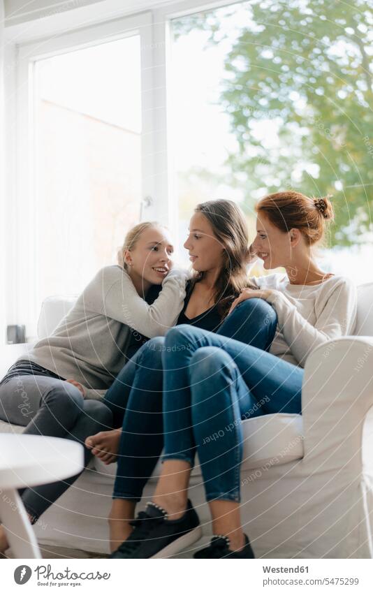 Happy mother with two teenage girls on couch at home happiness happy Teenage Girls female teenagers daughter daughters settee sofa sofas couches settees mommy