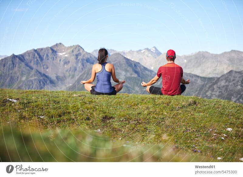 Man and woman meditating in the mountains, rear view Seated sit sports athletes Sportsman Sportsmen Sportspeople Sportsperson free Liberty peaceful peacefulness