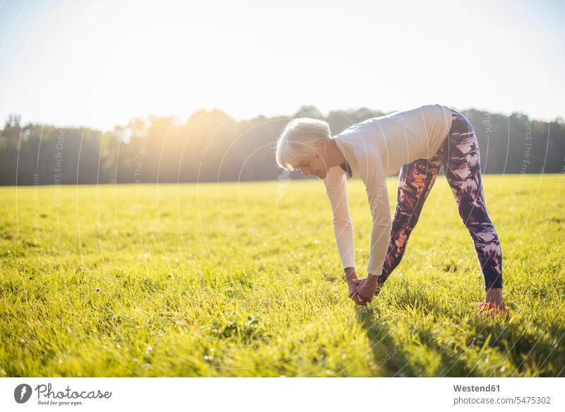 Senior woman doing gymnastics on rural meadow meadows country countryside females women stretching senior women elder women elder woman old senior woman Adults