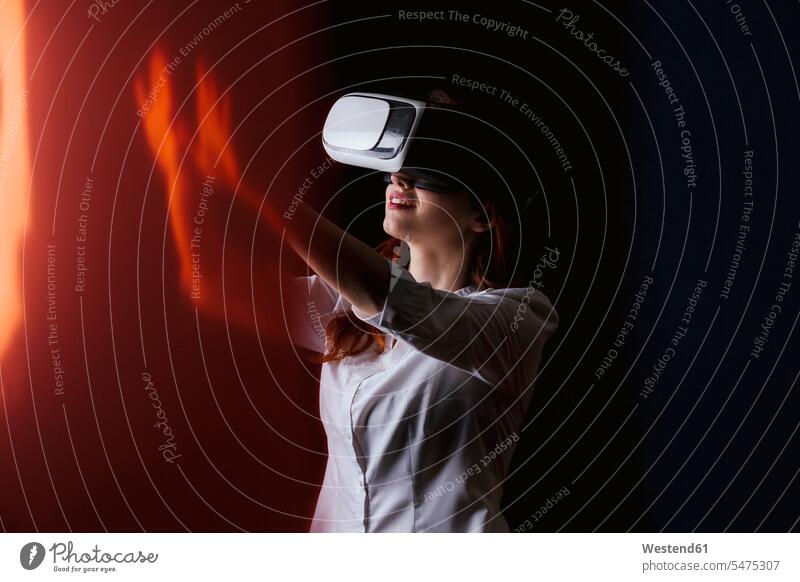 Young woman gesturing while using VR glasses over black background color image colour image studio shot studio photograph studio photographs studio shots